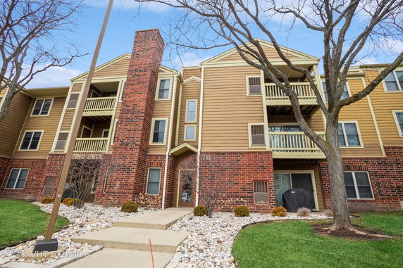 Front view of a multi-story residential building with brick and siding exterior.