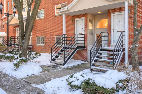Front view of a multi-story brick townhouse with exterior stairs.