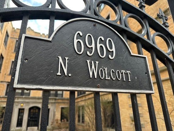 Front view of a building with an address sign on a metal gate.