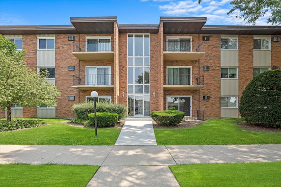 Front view of a multi-story brick apartment building with balconies.