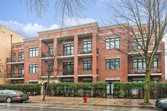 Front view of a three-story brick apartment building with balconies.