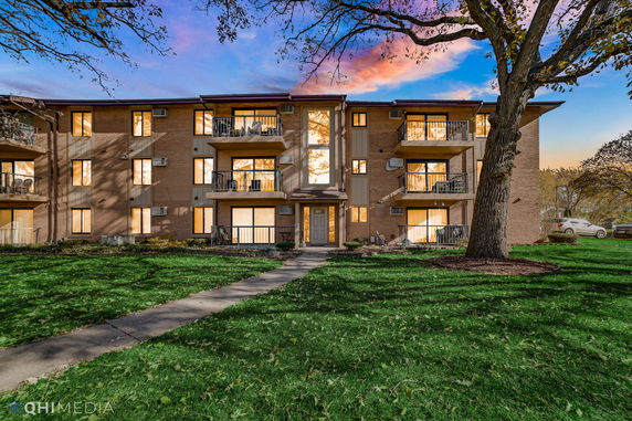 Front view of a three-story apartment building with balconies and large windows.