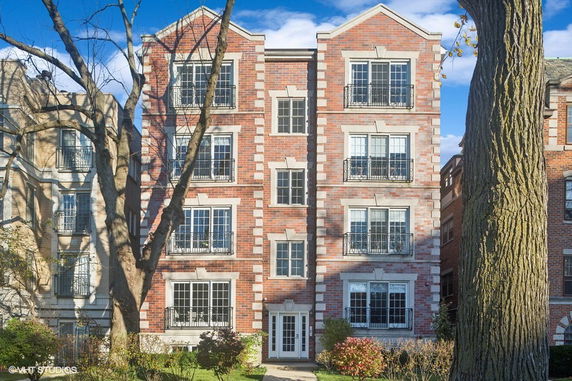 Front view of a multi-story brick apartment building with multiple balconies.