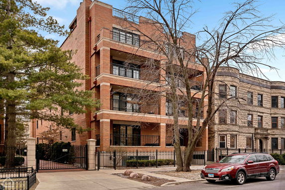 Front view of a multi-story brick apartment building with balconies.