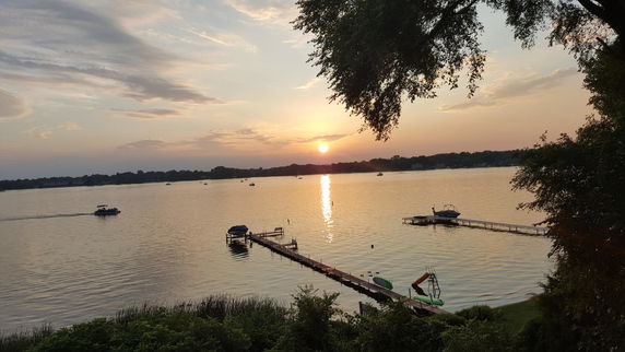 Panoramic view of a lake with several boats and docks at sunset.