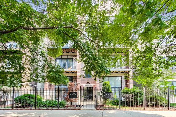Front view of a multi-story residential building with balconies and a gated entrance.