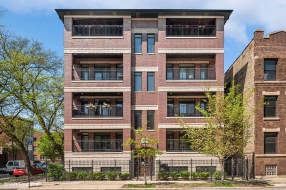Front view of a multi-story brick apartment building with balconies.