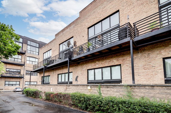 Front view of a multi-story brick building with balconies and large windows.
