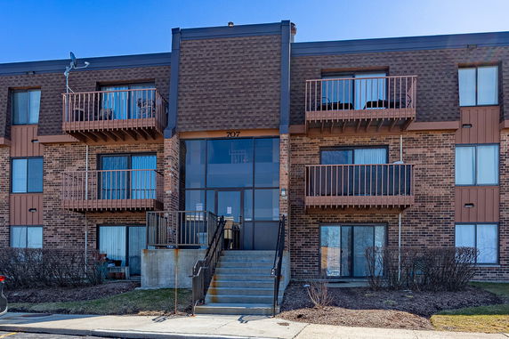Front view of a multi-story brick apartment building with balconies.