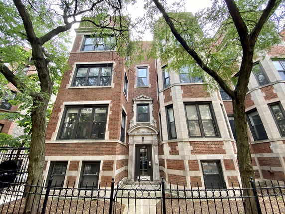 Front view of a multi-story brick building with large windows and ornate entrance.