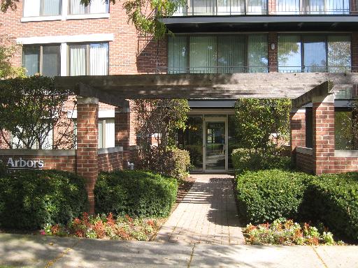 Entrance view of a multi-story brick building with a wooden pergola.
