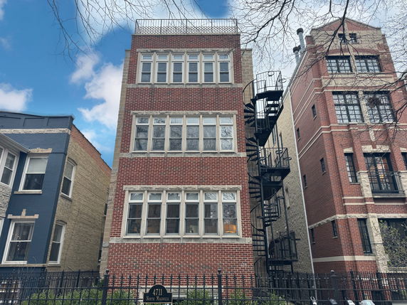 Front view of a multi-story brick building with an external spiral staircase.