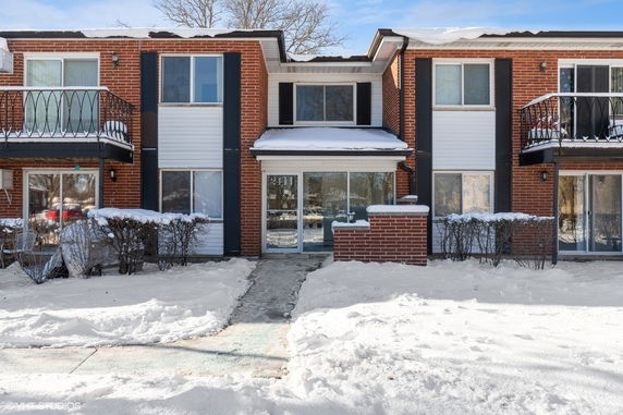 Front view of a two-story brick building with balconies and snowy surroundings.