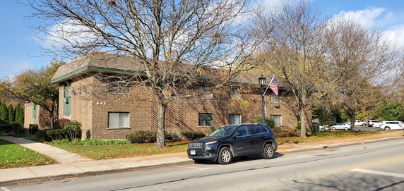 Front view of a two-story brick building with windows and a pitched roof.