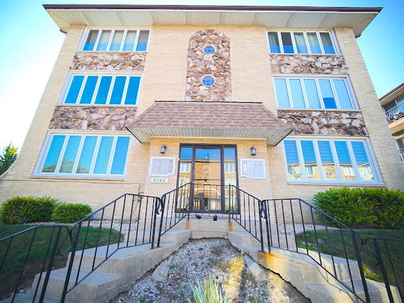 Front view of a multi-story building with large windows and decorative stone elements.