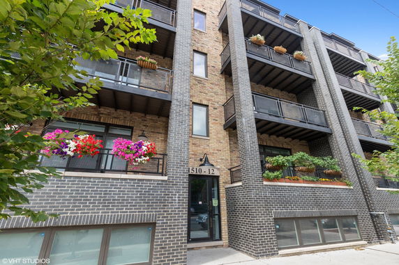 Front view of a multi-story building with balconies and plants.