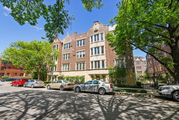 Front view of a multi-story brick apartment building with multiple windows.