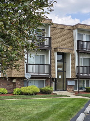 Front view of a multi-story building with brown siding and balconies.