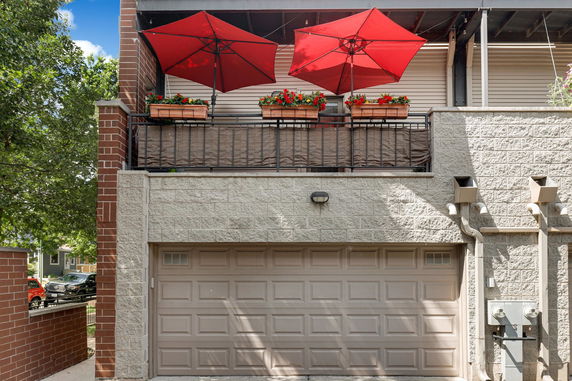 Front view of a house with a garage and a balcony with red umbrellas and flower pots.