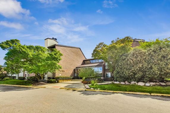 Front view of a commercial building with trees and landscaped surroundings.