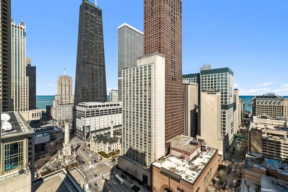 Aerial view of a cityscape with tall skyscrapers and a glimpse of a distant water body.