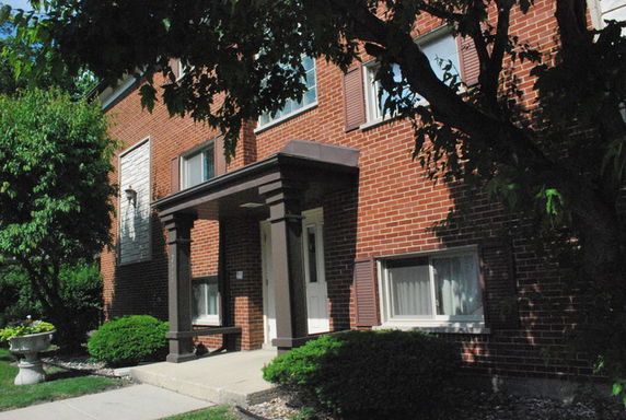 Front view of a brick two-story building with a porch.