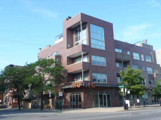 Front view of a multi-story commercial building with large windows and a dental studio on the ground floor.
