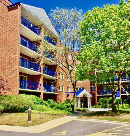 Front view of a multi-story apartment building with brick exterior and blue balconies.