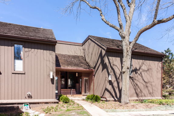 Front view of a two-story house with brown wooden siding and a gable roof.