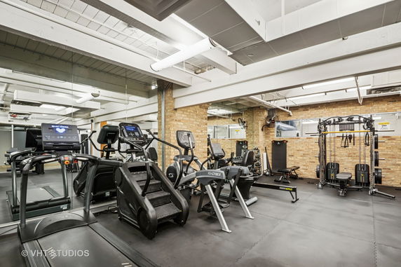Interior view of a gym with various exercise equipment and mirrored walls.