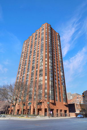 Front view of a tall, multi-story brick building with large windows.