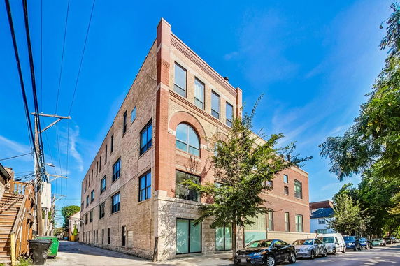 Front view of a multi-story brick building with large windows.