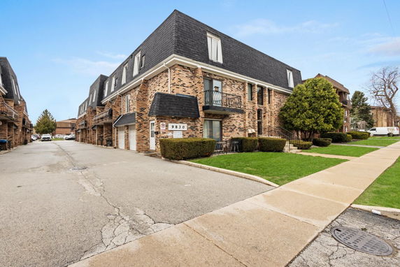 Front view of a multi-story brick building with a sloped roof.