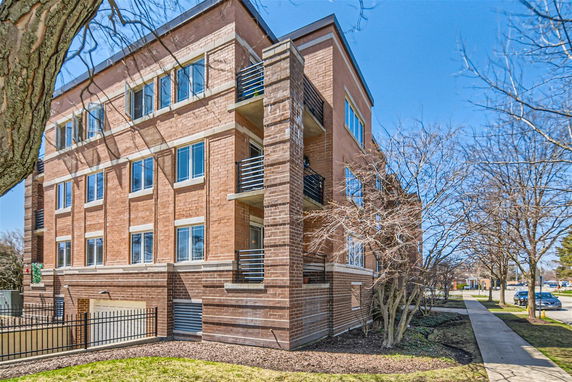 Front view of a multi-story brick building with balconies and large windows.