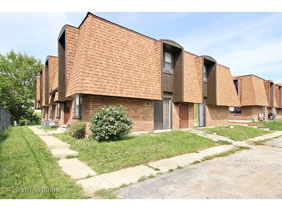 Front view of a row of brick townhouses with slanted roofs.
