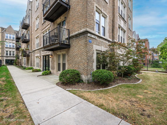 Front view of a multi-story residential building with brick exterior and balconies.