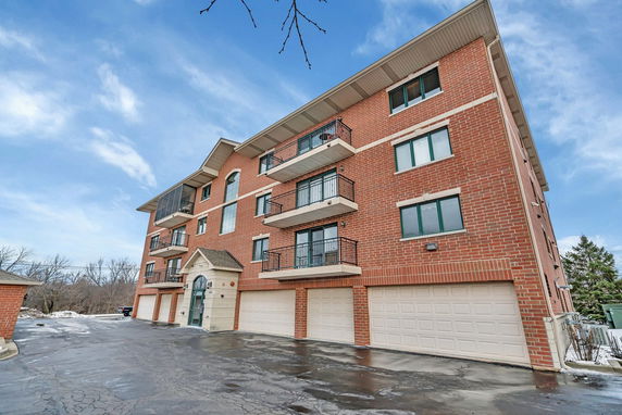 Front view of a multi-story brick building with balconies and garages.