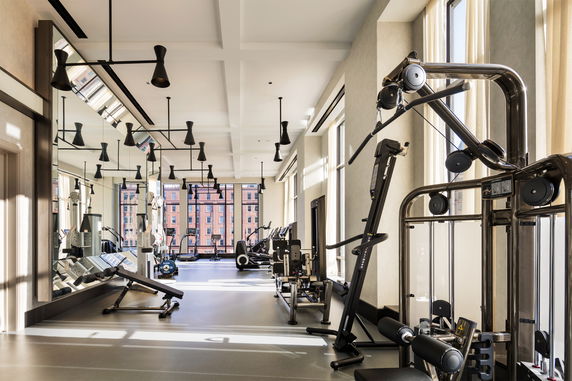 Interior view of a gym equipped with various exercise machines and large windows.