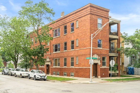 Front view of a three-story brick apartment building on a corner lot.