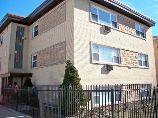 Front view of a three-story brick building with large windows and decorative stonework.