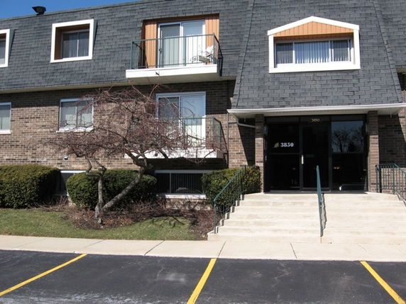 Front view of a multi-story apartment building with a sloped roof.