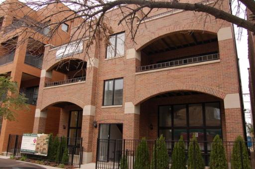 Front view of a multi-story brick building with arched balconies.