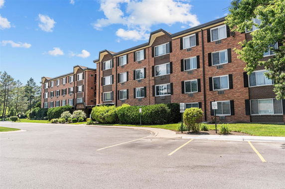 Front view of a multi-story brick apartment building with multiple windows.