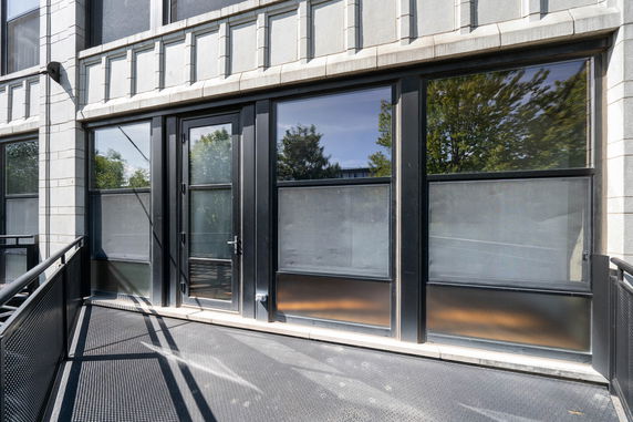 Front view of a building with large windows and a metal walkway.
