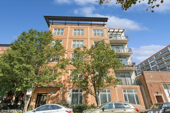 Front view of a multi-story brick apartment building with balconies.