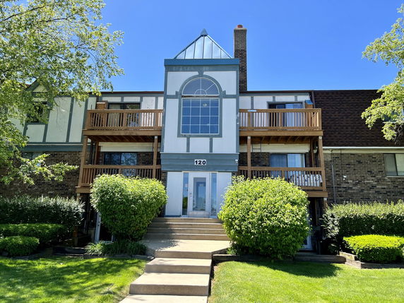Front view of a multi-story building with a central glass window and wooden balconies.