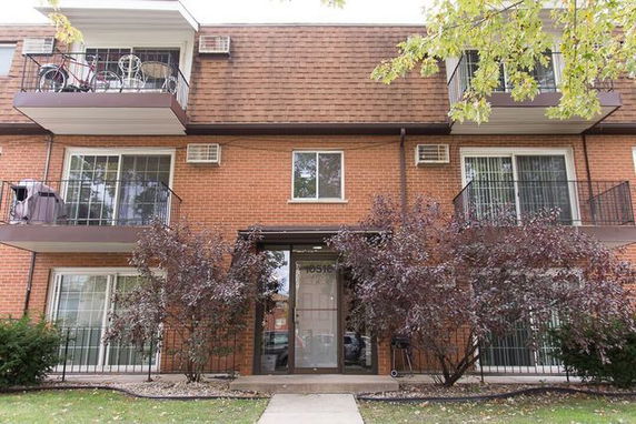Front view of a multi-story brick apartment building with balconies.