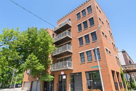 Front view of a multi-story brick apartment building with balconies.
