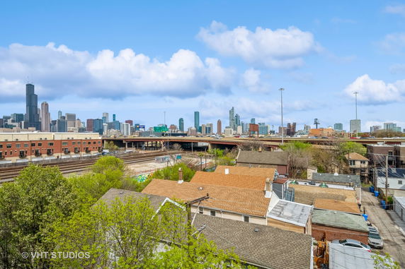 Panoramic view of city skyline with residential rooftops and railway tracks in the foreground.