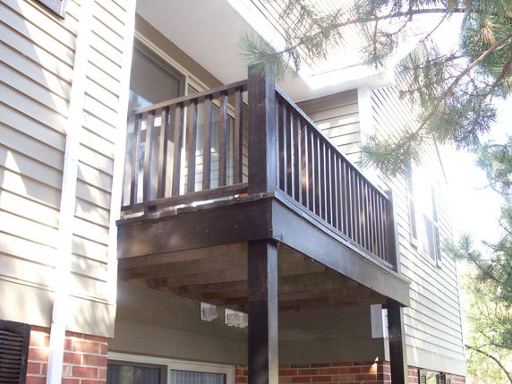 Side view of a house with a small balcony and wooden railing.